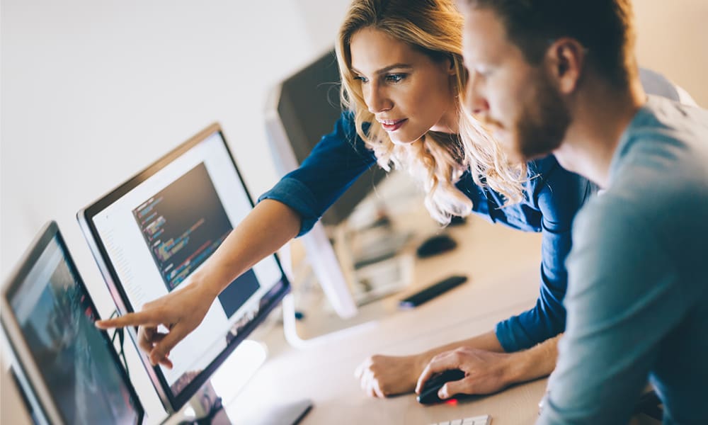Blog - Programmers Working While Pointing and Discussing in Front of Computers