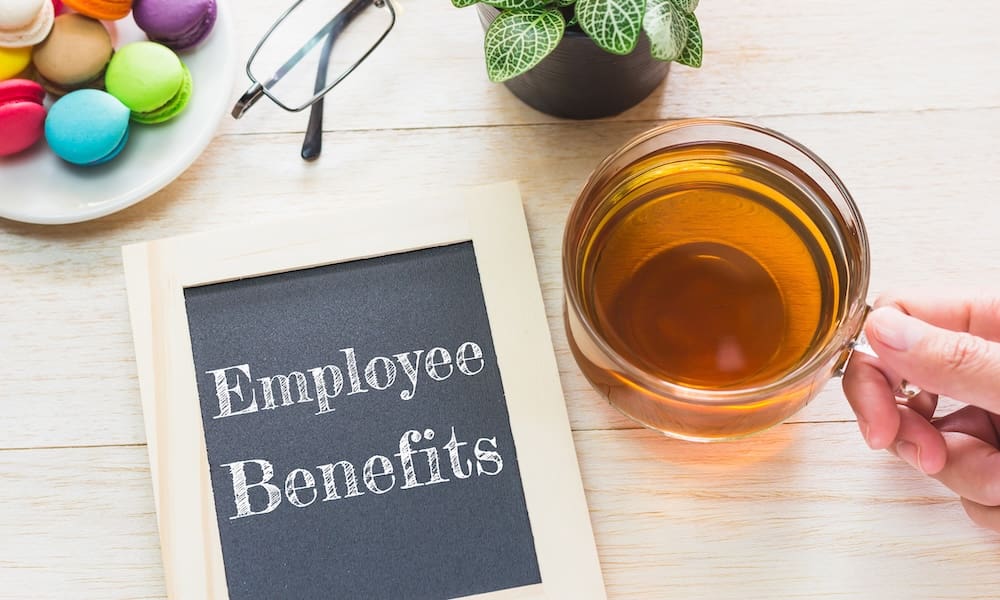 Concept Employee Benefits message on wood boards. Macaroons and glass Tea on table. Vintage tone.